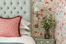 21 an eye-catchy bedroom with bold blue and red floral wallpaper, a mint upholstered bed with red printed and green bedding, a green and white floral nightstand