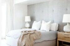 22 a clean neutral contemporary bedroom with a grey upholstered wall and an upholstered bed that matches, neutral textiles and a large rug