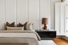 23 a fabulous contemporary bedroom with a headboard clad with upholstered panels, a bed with neutral earthy bedding and a matching bench, a large nightstand with a lamp