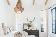 26 a neutral eclectic bedroom with wooden beams on the ceiling, a statement brass chandelier with candles