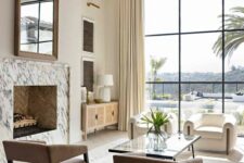 30 a refined Mediterranean living room done in neutral shades, with a marble clad fireplace, beige and creamy chairs, a glass coffee table and a glazed wall
