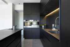 30 an ultra-minimalist black kitchen with sleek cabinets, a matching kitchen island and built-in lights is amazing