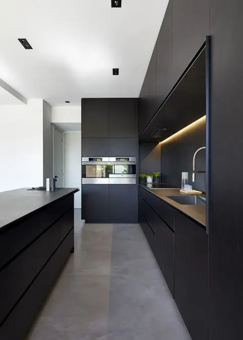 An ultra minimalist black kitchen with sleek cabinets, a matching kitchen island and built in lights is amazing