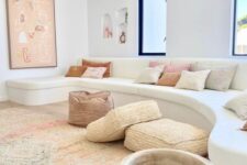 31 a chic minimal Mediterranean living room with a creamy curved sofa, neutral pillows, woven poufs and cushions, a large artwork