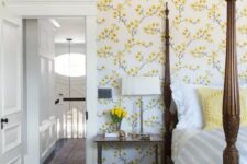 45 a vintage-inspired bedroom with yellow floral walls, a heavy bed with pillars, a chair and nightstands plus blooms