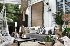 72 a boho outdoor living room with a jute rug and poufs, a sofa with black and white pillows, a low black table and a pendant chair