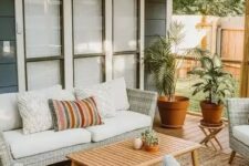 75 a cool modern outdoor living room with neutral woven furniture, printed pillows, a wooden table and potted plants welcomes