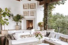 81 a neutral boho living room with a fireplace, a corner sofa with printed pillows, wood and metal tables and potted greenery