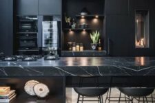 a black moody kitchen with plain cabinets and a stunning black marble kitchen island for a refined feel