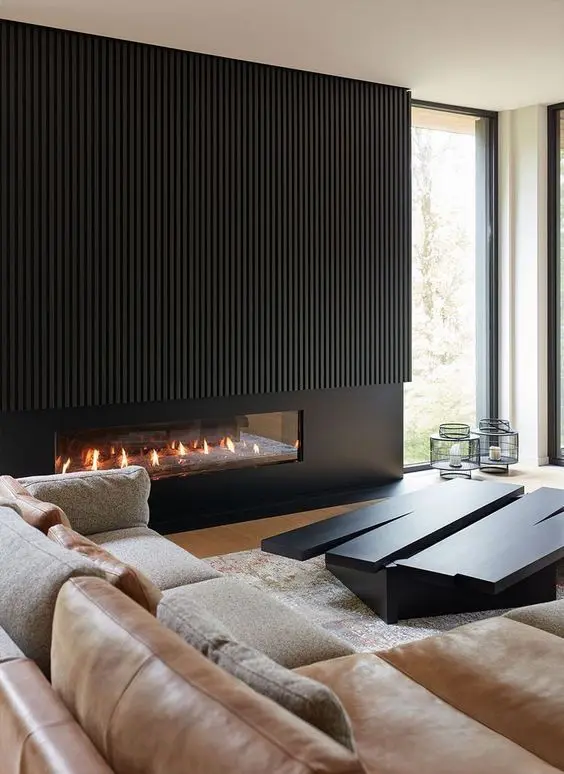 a chic minimalist living room with a black built-in fireplace with black wood over it, a neutral sofa, an eye-catchy black coffee table