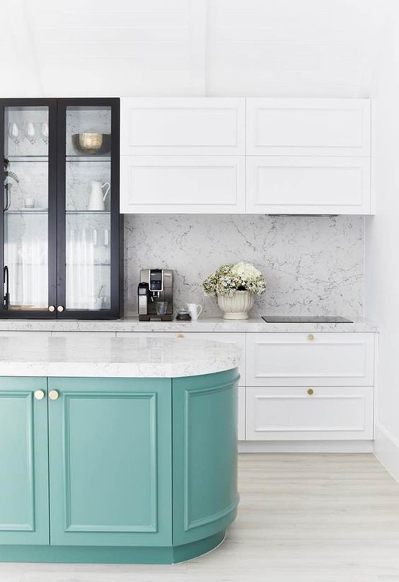 a chic white kitchen with shaker style cabinets and a black glass one for more drama, a turquoise curved kitchen island and white stone countertops