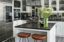 a cool black and white farmhouse kitchen with shaker cabinets, black countertops, a black and white tile floor