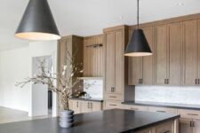 a farmhouse kitchen with stained cabinetry, a white tile backsplash, black countertops and black pendant lamps