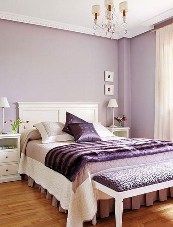 a feminine bedroom with lilac walls, purple accessories and an upholstered bench is a chic and refined idea