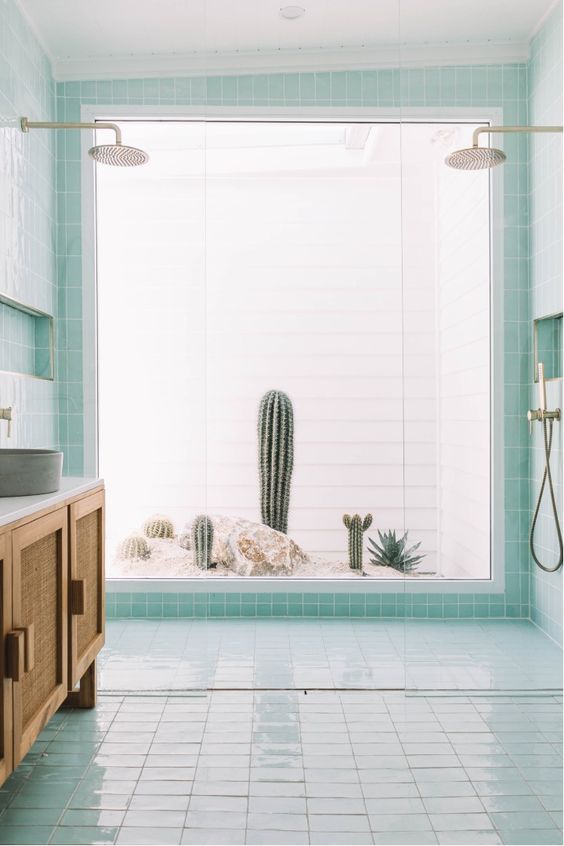 a lovely aqua bathroom with a shower that has a cacti view, a rattan vanity and concrete sinks is super cool
