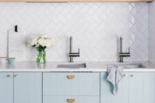 a lovely kitchen with light blue kitchen cabinets, a white tile backsplash and white countertops, an open shelf for displaying stuff