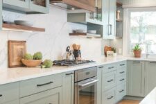 a lovely light green kitchen with shaker cabinets, open shelves, a white quartz backsplash and countertops and a matching kitchen island