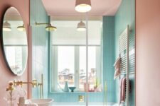 a lovely pastel bathroom with turquoise and pink walls, a pink vanity, brass and gold fixtures and a lovely view