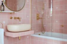 a lovely pink bathroom with pink star tiles, a floating vanity, a tub, gold fixtures and details