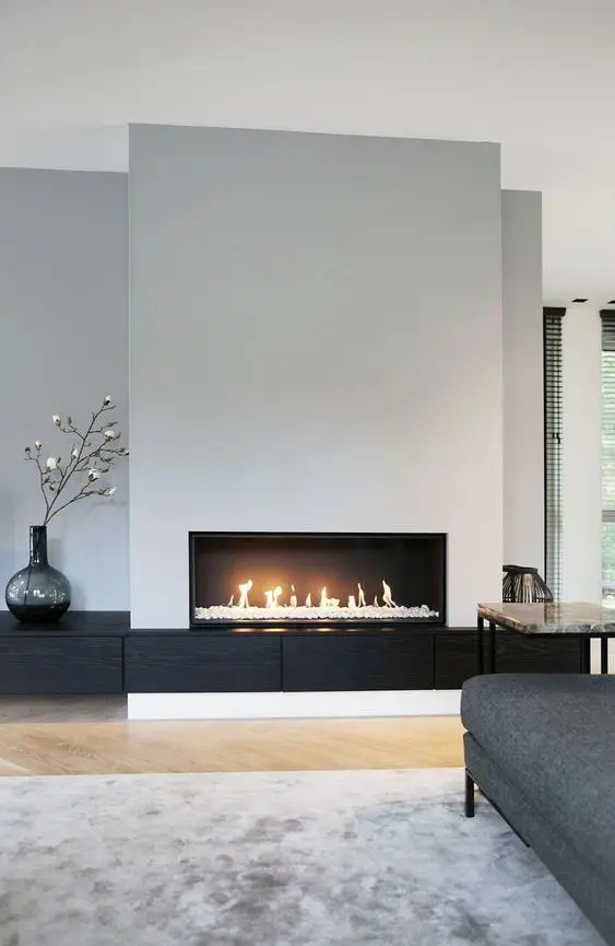 a minimal living room with an ethanol fireplace, a marble side table, a grey sofa and some decor