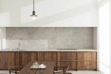 a minimalist kitchen with stained lower cabinets, a large white panel over them, a grey quartz backsplash and countertops