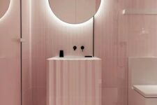 a minimalist light pink bathroom with black touches for depth and a mirror with built-in lights