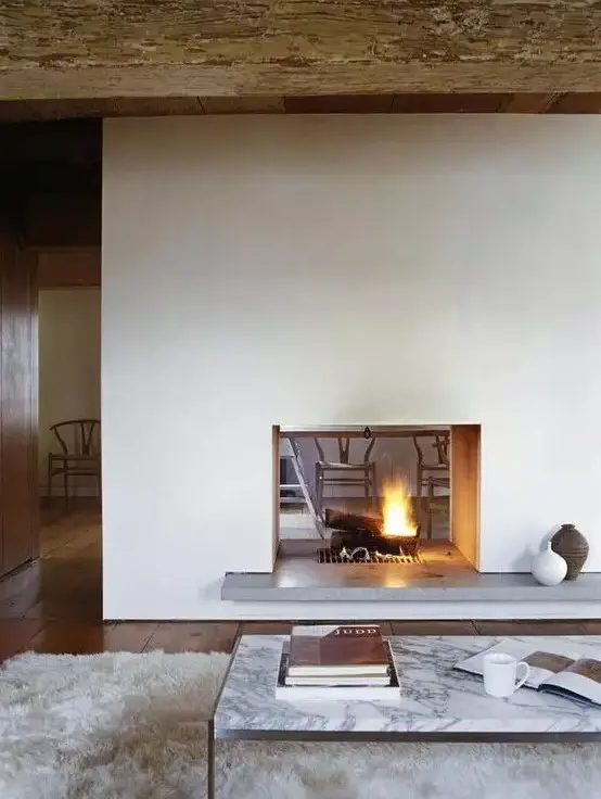 a minimalist white double-sided fireplace with a concrete stand is a cozying up and chic idea for a modern space