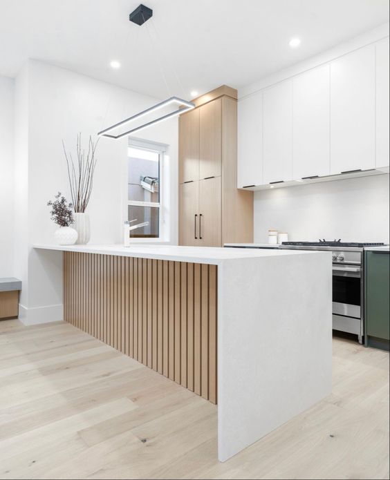 a modern kitchen with white and stained cabinets, built-in lights and a fluted kitchen island with a waterfall countertop