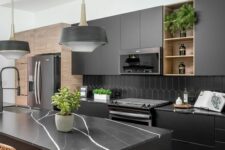 a modern matte black kitchen with a hex tile backsplash, black marble countertops, black pendant lamps and woven chairs