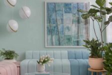 a pastel living room with mint blue walls, a color block floor, a color block blue sofa, a pink daybed, pendant lamps