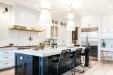 a sophisticated white kitchen with shaker cabinets, a black kitchen island, a large hood, a white quartz backsplash and matching countertops