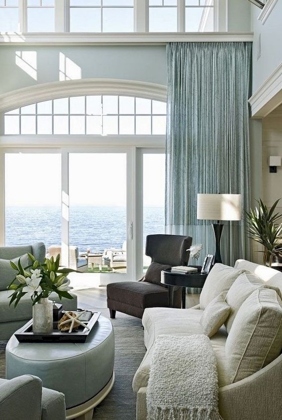 a stylish beach living room with an aqua curtain, aqua furniture, a dark chair and a creamy sofa