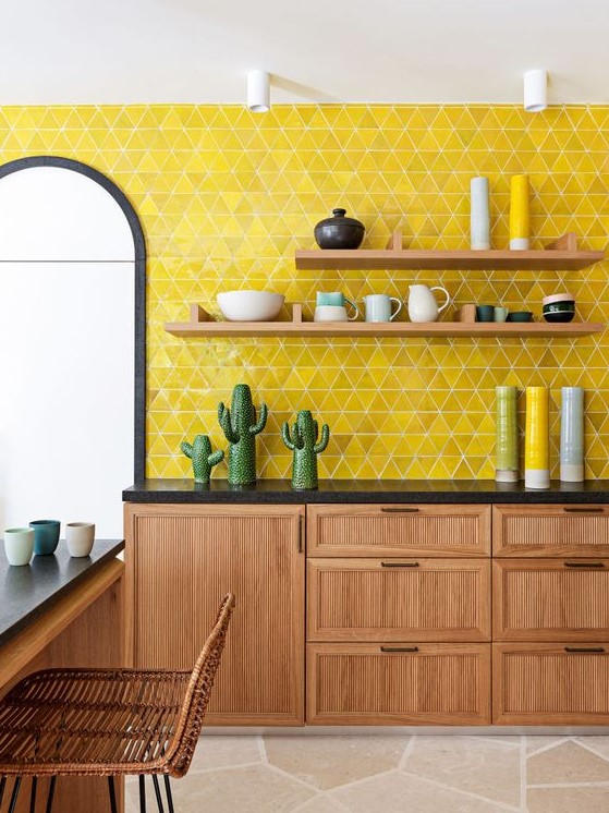 A stylish mid century modern kitchen with wooden cabinets and furniture, black countertops and a lemon yellow tile backsplash