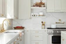 a very light grey kitchen with shaker cabinets, a white quartz backsplash and countertops and gold fixtures is pure elegance
