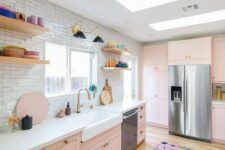 an eclectic kitchen with blush cabinets, a white tile backsplash, open shelves and colorful tableware