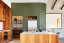 an eye-catchy mid-century modern kitchen with stained cabinets, a robust fluted kitchen island and a matching fluted curved green wall