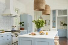 03 a beautiful coastal kitchen in light blue and white, with a mosaic tile backsplash, wicker lampshades and rattan stools plus greenery