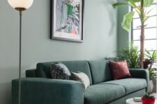 05 a modern living room with a sage green accent wall, a dark green sofa with printed pillows, a white side table and potted plants
