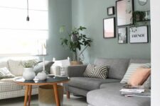08 a Scandinavian living room with sage gree walls, a windowpane print and grey sofa, printed pillows, a gallery wall and a coffee table