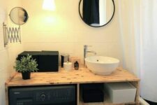 11 a small black and white bathroom with a black washing machine built in the vanity, a small mirror and a shower space