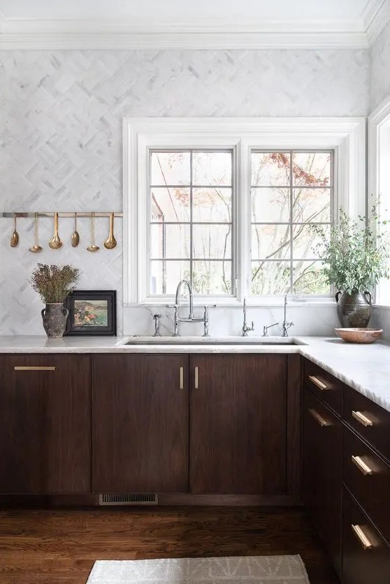 A jaw dropping walnut kitchen with white stone countertops and white marble tiles plus touches of gold