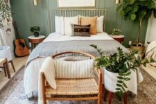 12 a modern bedroom with a sage green accent wall, a metal bed with neutral bedding, a woven chair, potted plants, gold touches for more elegance