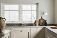 17 a warm and welcoming greige Scandinavian kitchen with vintage cabients and walls matching in color, dark countertops and a tiny backsplash