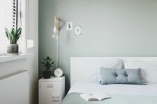 18 a Scandinavian bedroom with a white bed and green and white bedding, white metal cabinets, a pendant lamp and sconces
