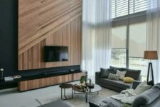 20 a contemporary double-height living room in the shades of grey, with an accent wood slat wall, a TV and a TV unit, double-height windows that bring a lot of light