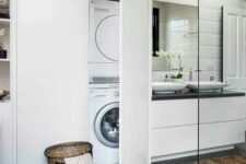 20 a modern bathroom clad with grey and white tiles, a white vanity with sinks, a large storage unit with a washing machine hidden