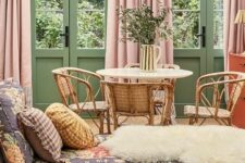 21 a muted color living room with green walls and doors, pink curtains, a floral daybed and a rattan dining nook
