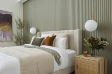 22 a stylish modern bedroom with a sage green fluted accent wall, a neutral upholstered bed with neutral bedding, rattan nightstands and pendant lamps