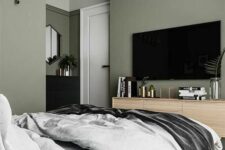 23 a stylish modern bedroom with sage green walls, an upholstered grey bed with grey bedding, a stained dresser and a black one