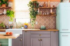 25 a colorful kitchen with orange walls, grey cabinetry, a mint blue fridge, a matching kitchen island and a bold orange printed tile backsplash